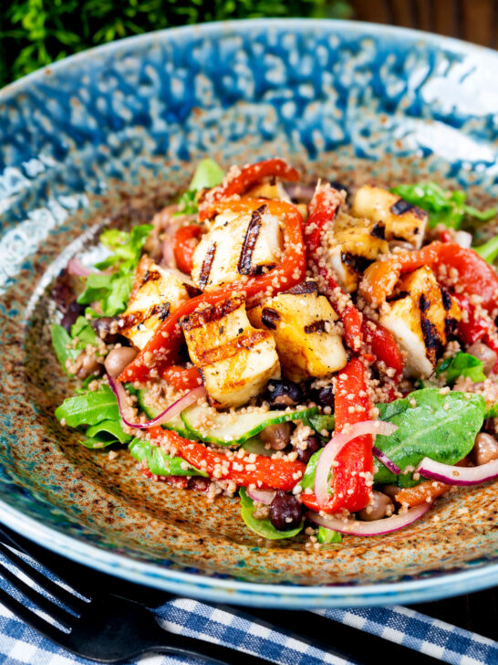 Close-up grilled and marinated halloumi salad with peppers, couscous and chickpeas.