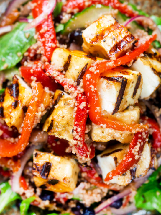 Overhead close-up grilled and marinated halloumi salad with peppers, couscous and chickpeas.