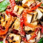 Overhead close-up grilled and marinated halloumi salad with peppers, couscous and chickpeas featuring a title overlay.