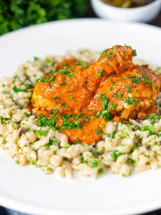 Hungarian chicken paprikash or csirkepaprikás in a paprika sauce with nokedli.