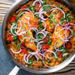 Overhead Indian influenced one pot baked chicken legs and rice in a skillet.