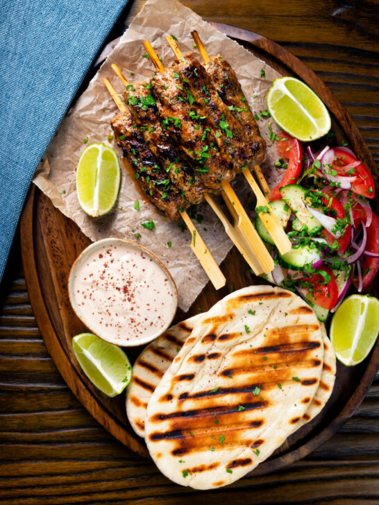 Overhead lamb kofta kebabs with pitas, salad and pomegranate yoghurt dip.