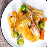 Overhead roast guinea fowl with honey glazed vegetables.