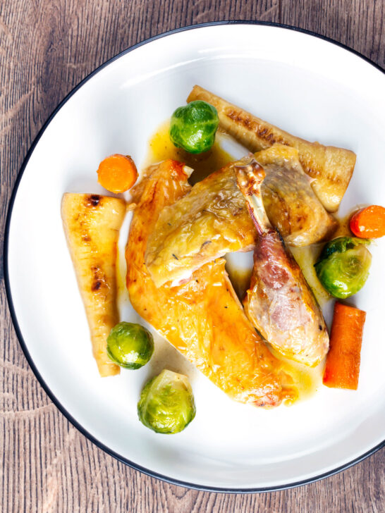 Overhead roast guinea fowl with honey glazed vegetables.