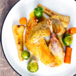 Overhead roast guinea fowl with honey glazed vegetables featuring a title overlay.