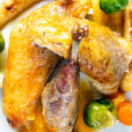 Close-up overhead Roasted guinea fowl with honey glazed vegetables and cider sauce.