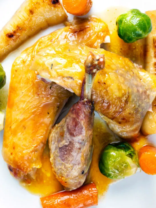 Close-up overhead Roasted guinea fowl with honey glazed vegetables and cider sauce.