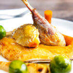Close-up roasted guinea fowl with honey glazed vegetables.