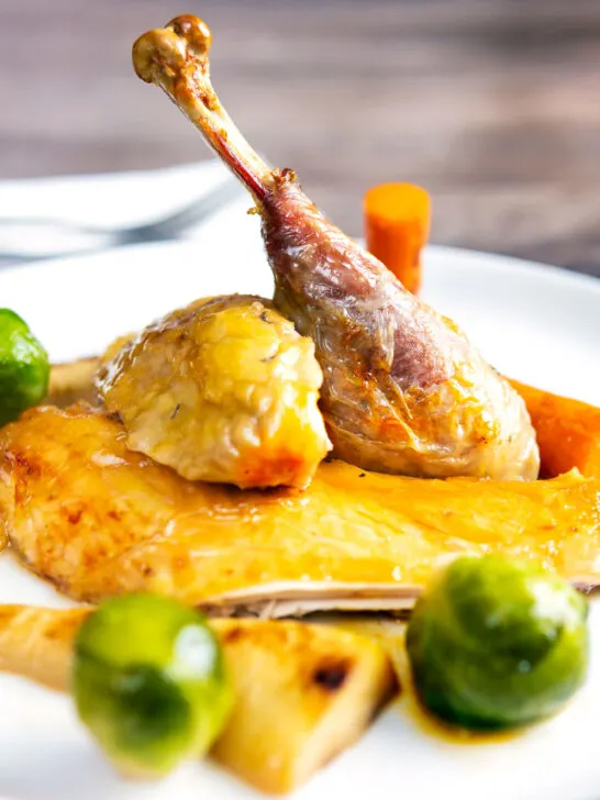 Close-up roasted guinea fowl with honey glazed vegetables.