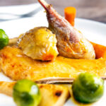 Close-up roasted guinea fowl with honey glazed vegetables featuring a title overlay.