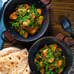 Overhead spinach and potato curry or saag aloo served with homemade chapatis.