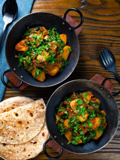 Overhead spinach and potato curry or saag aloo served with homemade chapatis.