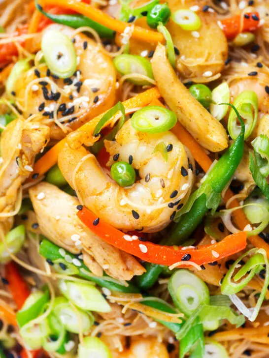 Overhead close-up curried Singapore chow mein noodles with chicken and prawns.