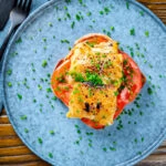 Overhead smoked haddock rarebit on toast with tomatoes garnished with chives.