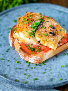 Smoked haddock rarebit on toast with tomatoes garnished with chives.