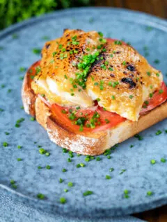 Smoked haddock rarebit on toast with tomatoes garnished with chives.