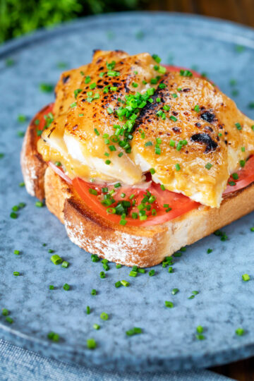 Smoked haddock rarebit on toast with tomatoes garnished with chives.