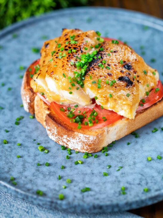 Smoked haddock rarebit on toast with tomatoes garnished with chives.