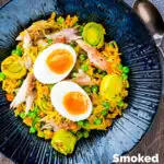 Overhead easy smoked mackerel kedgeree with leeks, peas topped and a boiled egg featuring a title overlay.