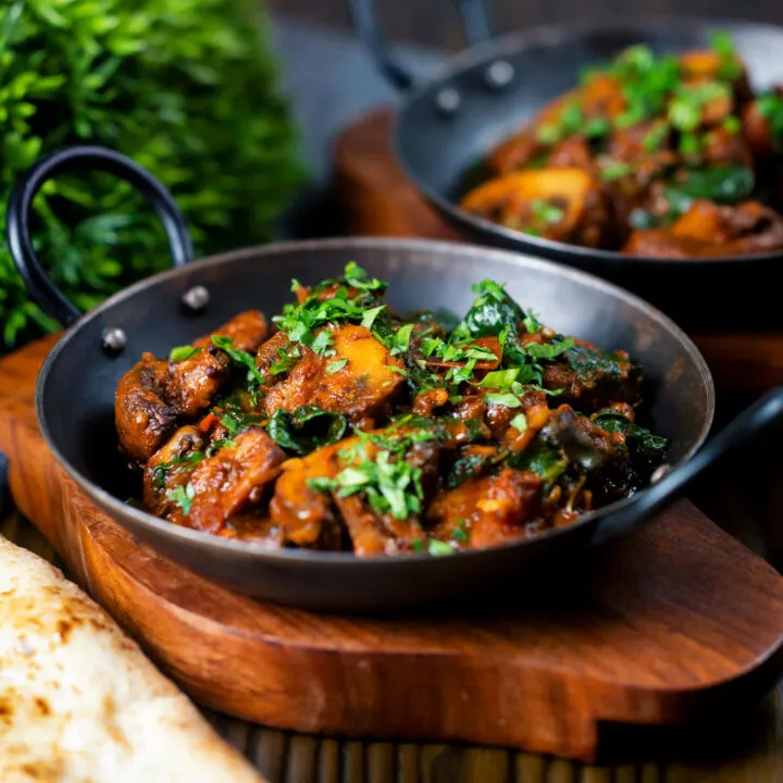 Vegan Indian mushroom and spinach or saag curry in an iron karai.