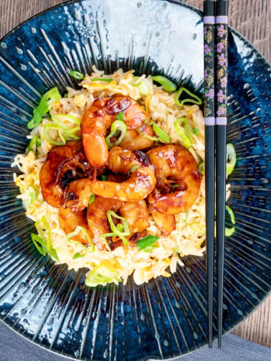 Overhead quick spicy teriyaki prawns or shrimp stir fry served with egg fried rice.