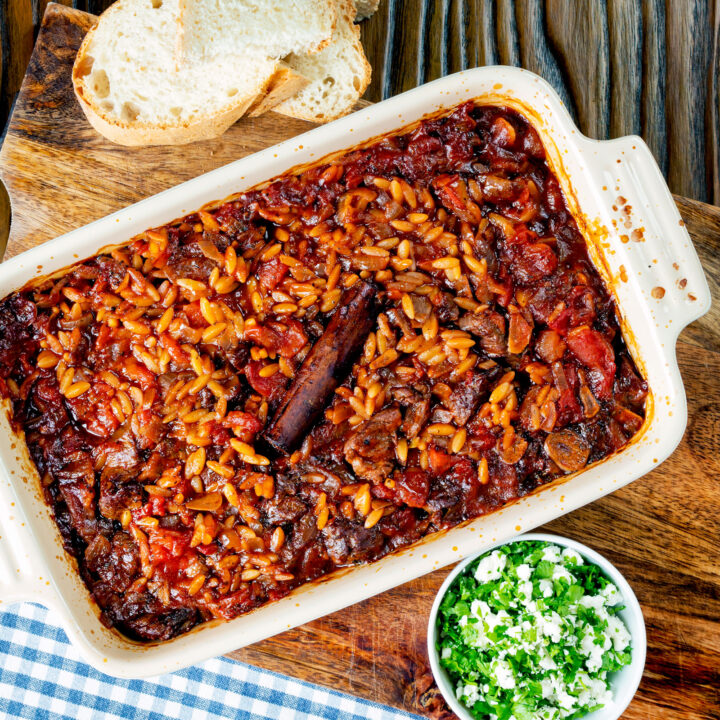 Greek baked lamb and orzo youvetsi or giouvetsi in a baking dish with parsley and feta.