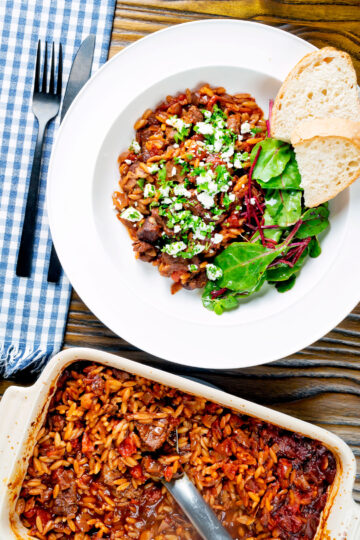 Overhead Greek baked youvetsi or giouvetsi with lamb and orzo in tomato sauce.
