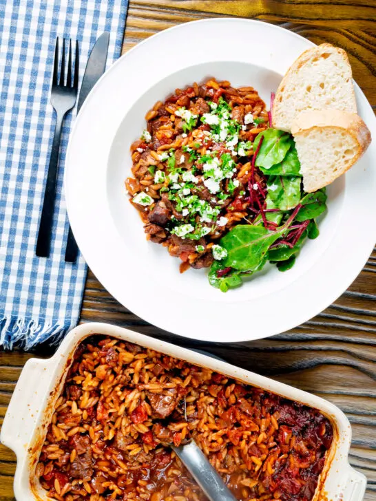 Overhead Greek baked youvetsi or giouvetsi with lamb and orzo in tomato sauce.