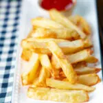 Air fryer golden crispy British chips served with a bowl of ketchup.