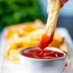 British style air fryer chips with one being dipped into tomato ketchup.