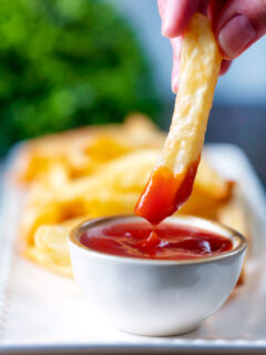 British style air fryer chips with one being dipped into tomato ketchup.