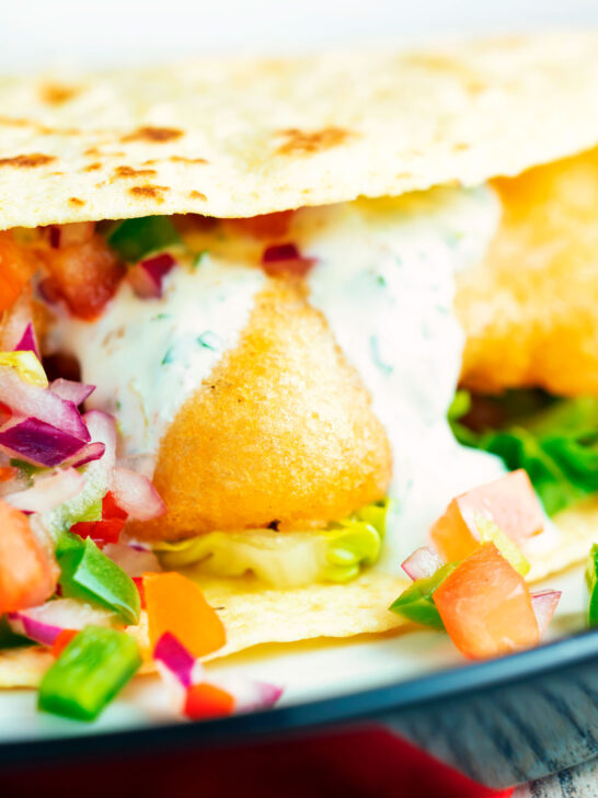 Close-up beer battered crispy cod fish tacos in a corn tortilla.