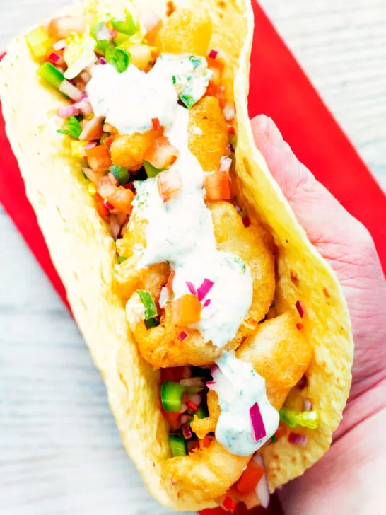 Overhead beer battered crispy cod fish tacos in a corn tortilla.