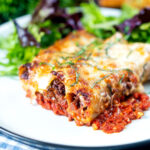Minced beef stuffed cannelloni with bechamel and mozzarella cheese served on a plate.