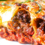 Close-up beef stuffed cannelloni with bechamel and mozzarella cheese served on a plate.
