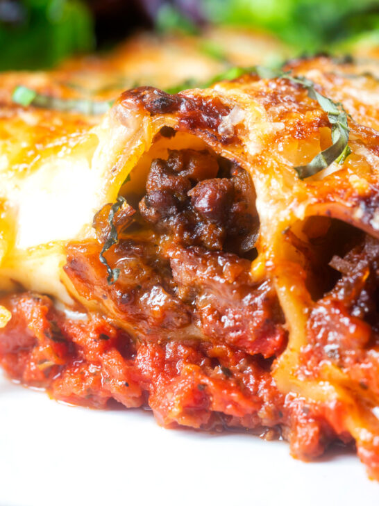 Close-up beef stuffed cannelloni with bechamel and mozzarella cheese served on a plate.