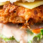 Close-up buttermilk fried chicken burger with a bitter chicory slaw and Swiss cheese.