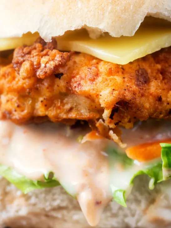 Close-up buttermilk fried chicken burger with a bitter chicory slaw and Swiss cheese.