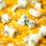 Close-up butternut squash and sage risotto served with Roquefort cheese.