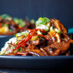 Close up steak and shiitake mushroom stir fry serve with rice.