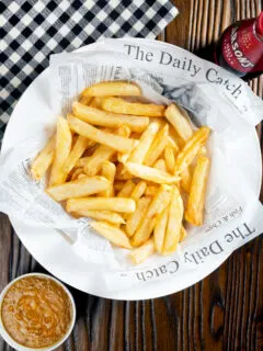 Overhead chip shop style chippy chips served with a side of curry sauce.