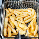 Chip shop style chippy chips cooking in a deep fat fryer.