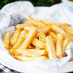 Chip shop style chippy chips served with a side of curry sauce.