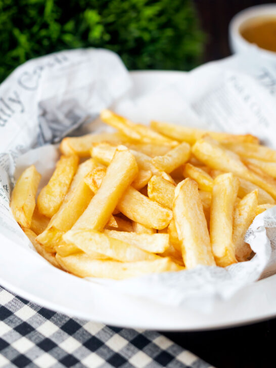 Chip shop style chippy chips served with a side of curry sauce.