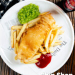 Overhead chip shop style fried battered fish served with chips and mushy peas featuring a title overlay.