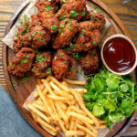 Overhead crispy fried buttermilk chicken wings with fries and sauce.