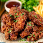 Crispy fried buttermilk chicken wings with fries and sauce.