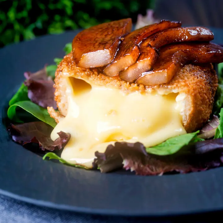 Deep fried camembert cut open to show perfectly melted cheese, served with balsamic pears.
