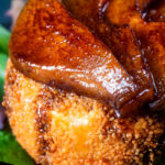 Close up balsamic glazed pears sat on couscous coated fried camembert cheese.