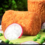 Close-up fried crumbed goat cheese with sweet pea puree, radishes and spring onions.